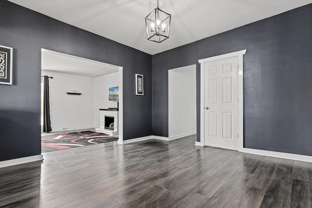 interior space with baseboards, a notable chandelier, a textured ceiling, and wood finished floors
