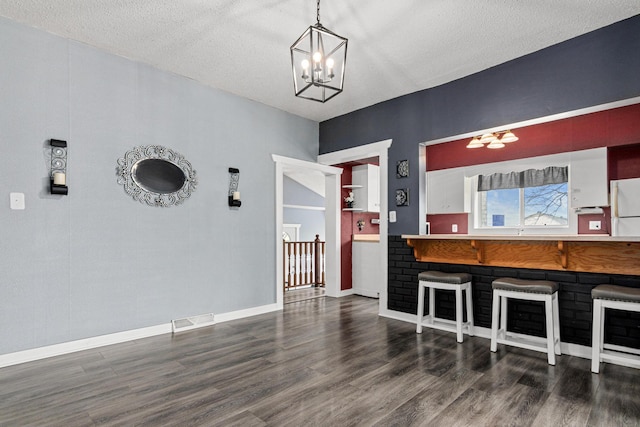 dining room featuring an inviting chandelier, a textured ceiling, visible vents, and wood finished floors