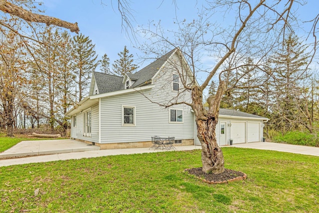 view of side of property with a yard, driveway, a shingled roof, and a garage