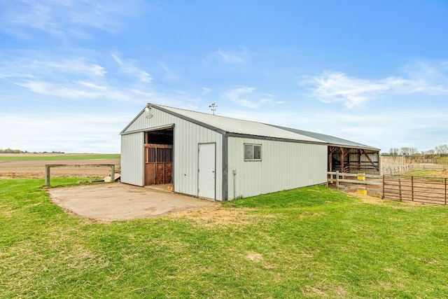 view of pole building featuring a yard, fence, and an exterior structure