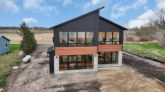 rear view of property with a sunroom and stone siding