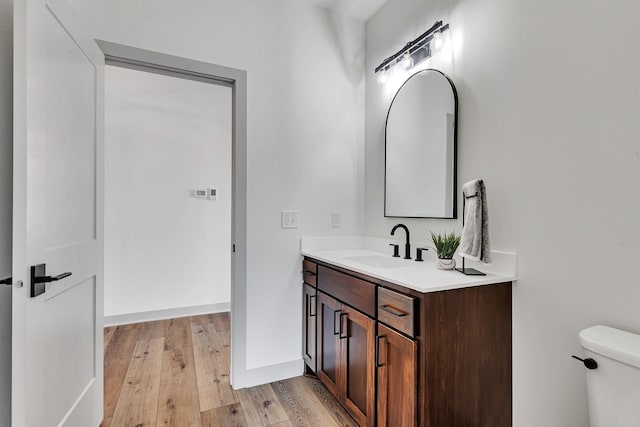 bathroom featuring wood finished floors, vanity, toilet, and baseboards