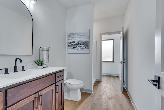 bathroom with wood finished floors, toilet, and vanity