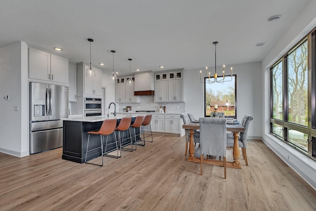 dining space with a chandelier, light wood-style flooring, baseboards, and recessed lighting