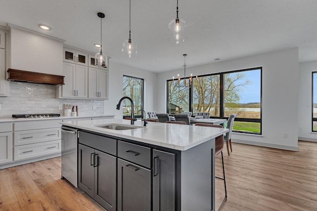 kitchen with a sink, light countertops, a kitchen island with sink, gas stovetop, and recessed lighting