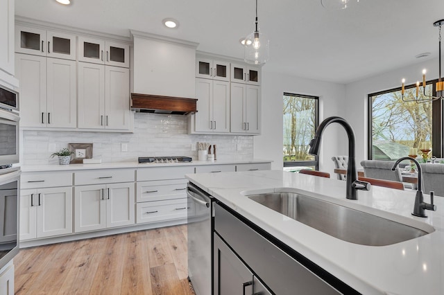 kitchen with a sink, decorative light fixtures, tasteful backsplash, light wood finished floors, and recessed lighting