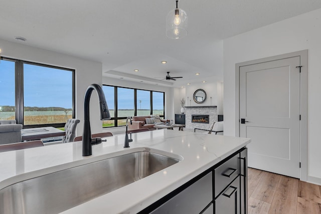 kitchen with a sink, a stone fireplace, light wood-type flooring, and open floor plan