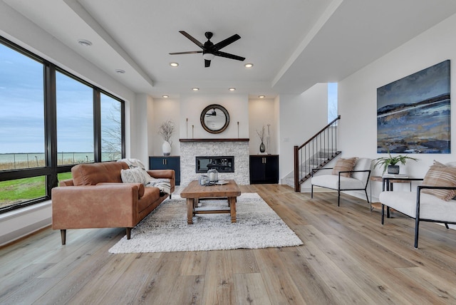 living area featuring healthy amount of natural light, ceiling fan, recessed lighting, wood finished floors, and a stone fireplace
