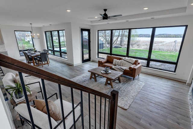 living room featuring light wood finished floors, a chandelier, baseboards, a ceiling fan, and recessed lighting