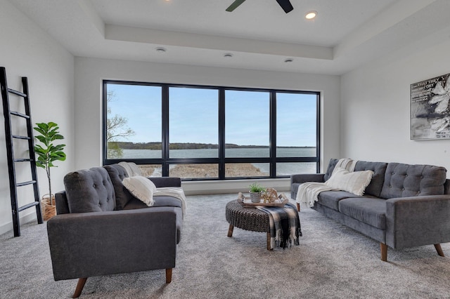 carpeted living area featuring plenty of natural light, recessed lighting, a water view, and a raised ceiling