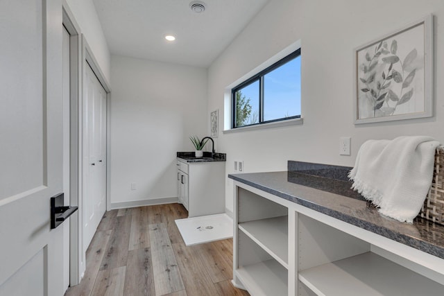 interior space featuring light wood-style floors, recessed lighting, a sink, and baseboards
