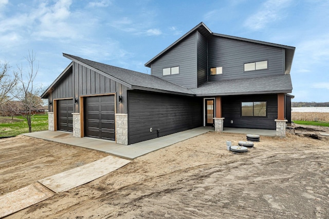 view of front of property featuring a garage, board and batten siding, a shingled roof, stone siding, and covered porch
