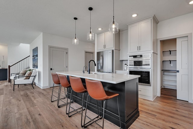 21070 Eagle Dr, Osakis, MN 56360 - kitchen featuring stainless steel appliances, a sink, an island with sink, light wood finished floors, and a breakfast bar