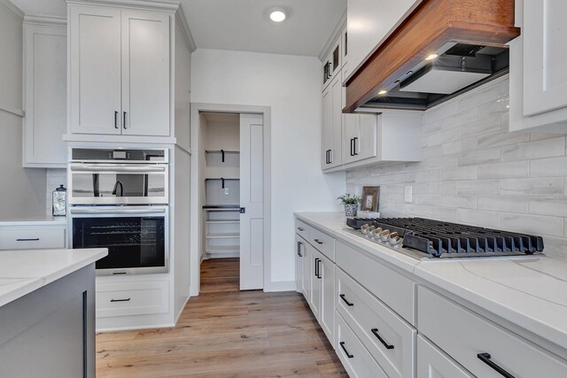 21070 Eagle Dr, Osakis, MN 56360 - kitchen with custom range hood, appliances with stainless steel finishes, tasteful backsplash, light wood-style floors, and light stone counters