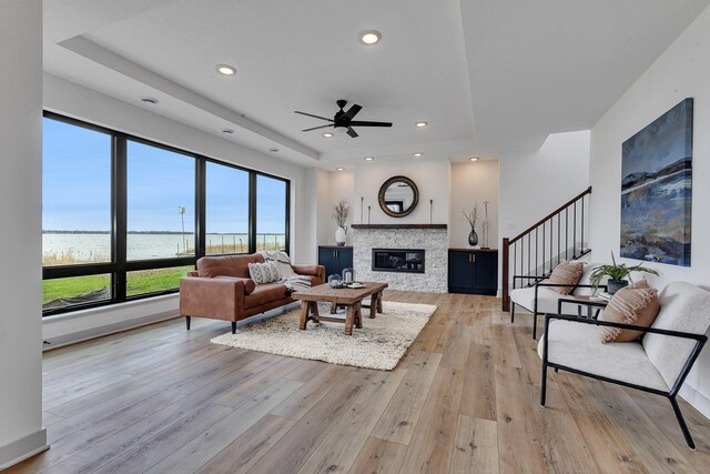 21070 Eagle Dr, Osakis, MN 56360 - living room with a water view, a ceiling fan, a tray ceiling, light wood-style floors, and a fireplace