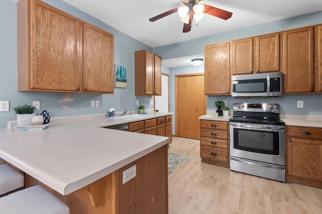 1226 Crystal Pl E, Chaska, MN 55318 - kitchen featuring stainless steel appliances, light countertops, light wood-style floors, a peninsula, and a breakfast bar