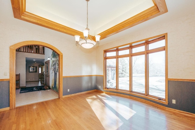 15671 Wermager Beach Rd, Lake Park, MN 56554 - empty room featuring a wainscoted wall, a tray ceiling, a chandelier, wood finished floors, and arched walkways