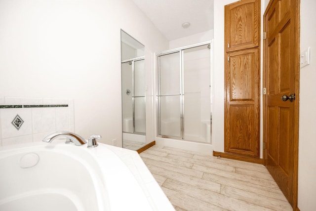 15671 Wermager Beach Rd, Lake Park, MN 56554 - bathroom featuring a stall shower, a garden tub, and wood finished floors