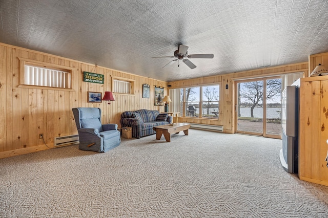 32331 Loon Dr, Candor Twp, MN 56587 - living room with a baseboard radiator, carpet floors, a ceiling fan, wood walls, and an ornate ceiling