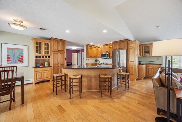5427 Twin Lake Blvd E, Brooklyn Center, MN 55429 - kitchen featuring appliances with stainless steel finishes, a kitchen breakfast bar, light wood-style flooring, a sink, and dark countertops