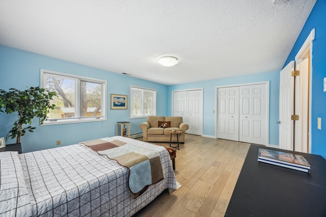 5427 Twin Lake Blvd E, Brooklyn Center, MN 55429 - bedroom with two closets, hardwood / wood-style floors, baseboard heating, a textured ceiling, and baseboards