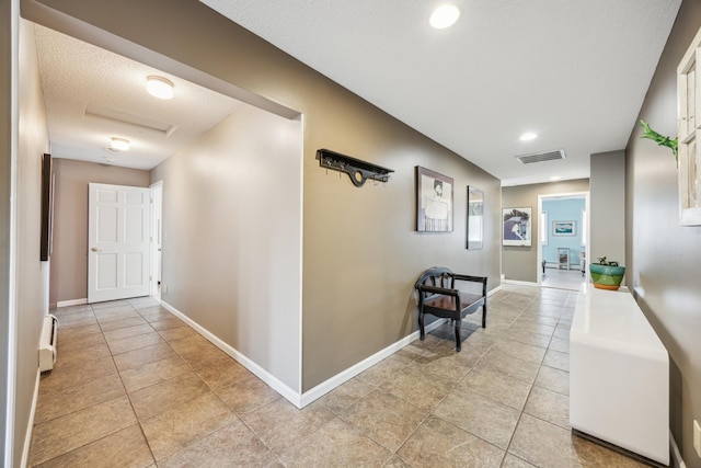 5427 Twin Lake Blvd E, Brooklyn Center, MN 55429 - hallway with light tile patterned floors, attic access, baseboards, a baseboard heating unit, and a textured ceiling