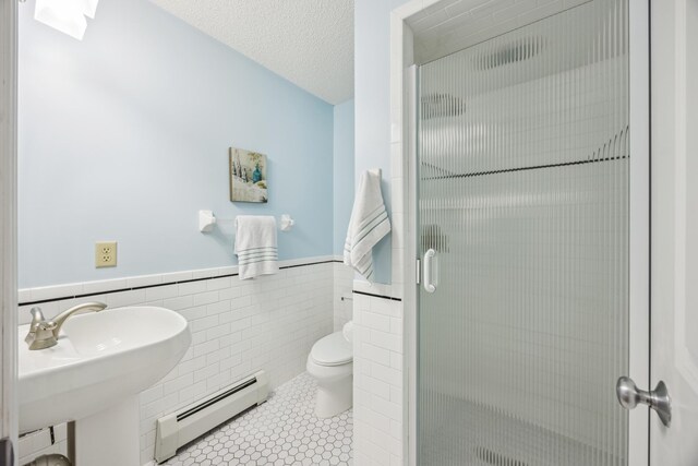 5427 Twin Lake Blvd E, Brooklyn Center, MN 55429 - full bath with a baseboard heating unit, a shower stall, toilet, a wainscoted wall, and tile walls