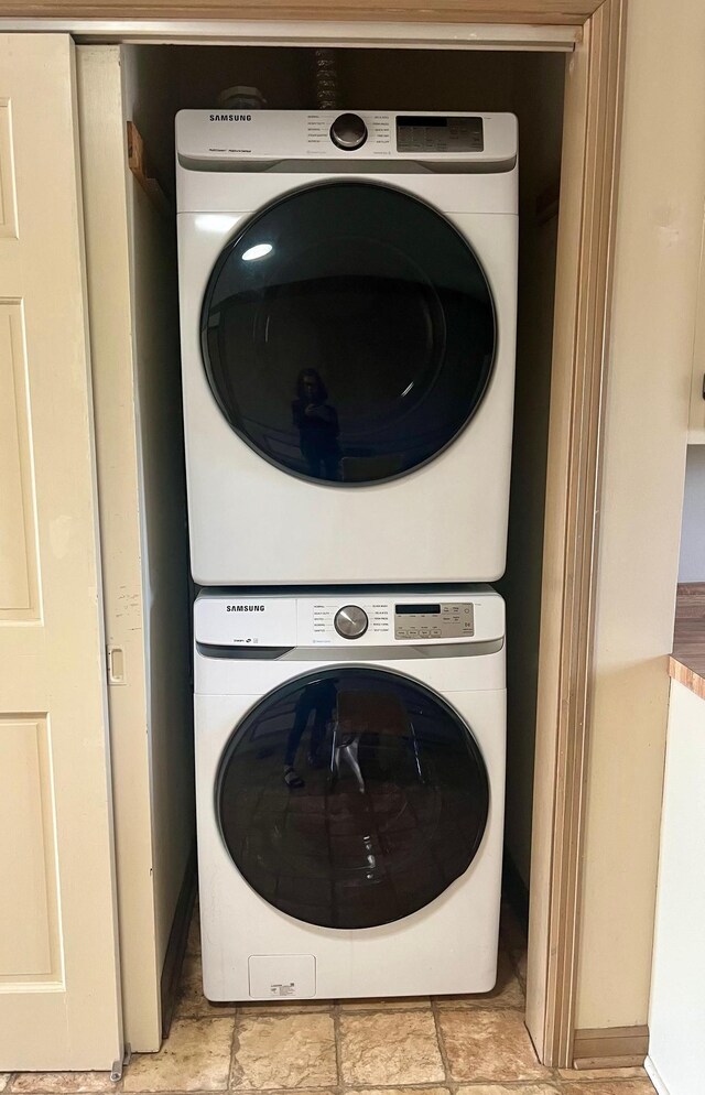 washroom featuring stacked washer and dryer, laundry area, and baseboards