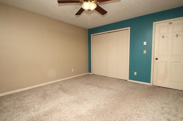 unfurnished bedroom featuring baseboards, carpet, ceiling fan, and a closet