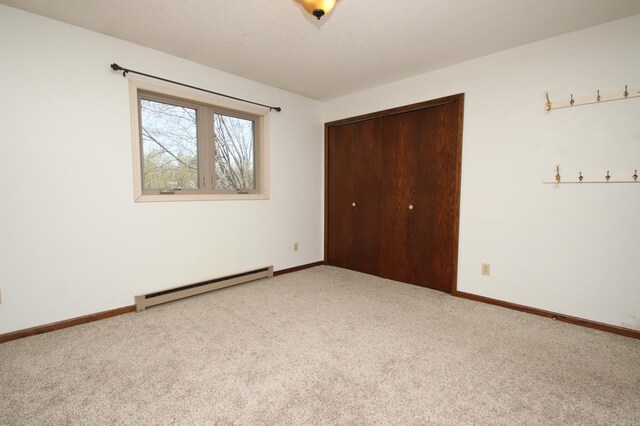 unfurnished bedroom featuring a closet, a baseboard radiator, carpet, and baseboards
