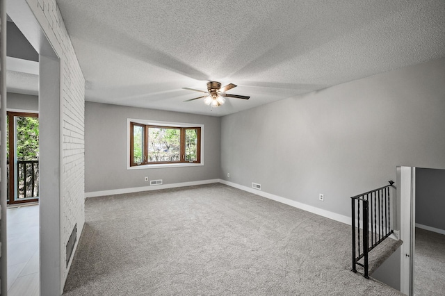 empty room with a ceiling fan, carpet, a textured ceiling, and baseboards