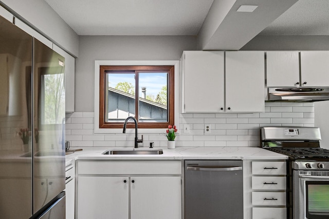 kitchen with appliances with stainless steel finishes, under cabinet range hood, a sink, and white cabinetry