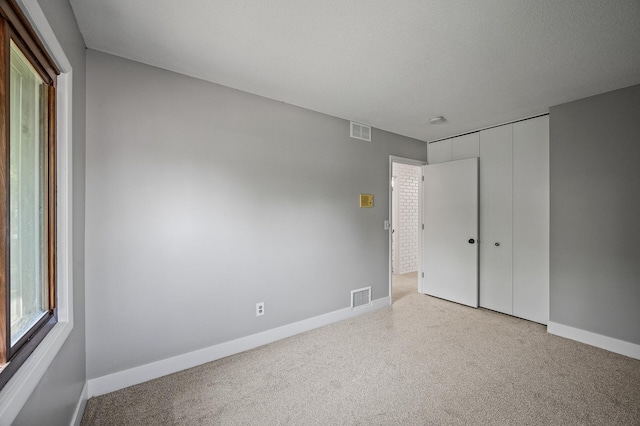unfurnished bedroom with light carpet, baseboards, and a closet