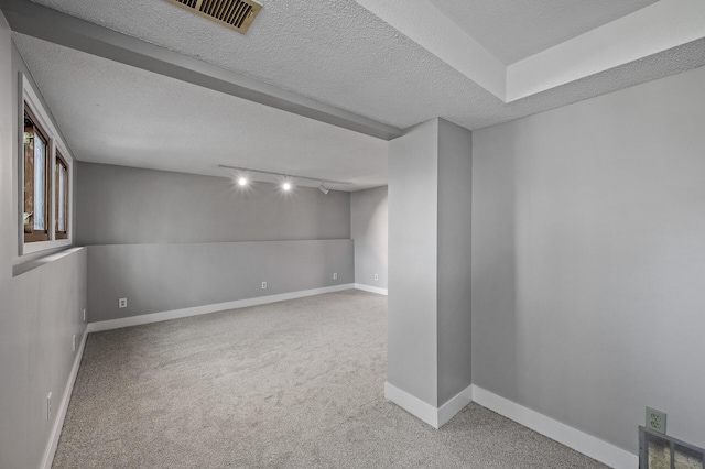 basement featuring track lighting, carpet floors, baseboards, and a textured ceiling