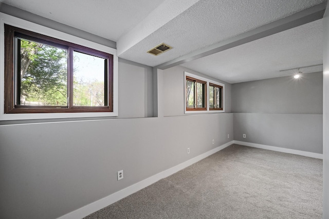 carpeted spare room featuring baseboards, a textured ceiling, and track lighting