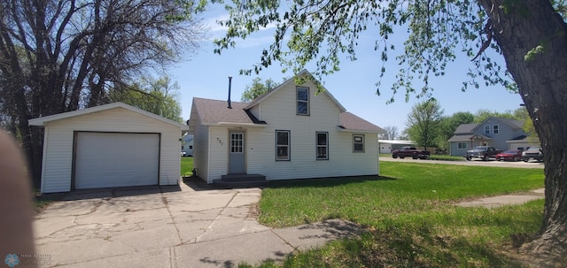 721 Front St, Hawley, MN 56549 - view of front facade featuring concrete driveway, an outdoor structure, a detached garage, a front yard, and roof with shingles