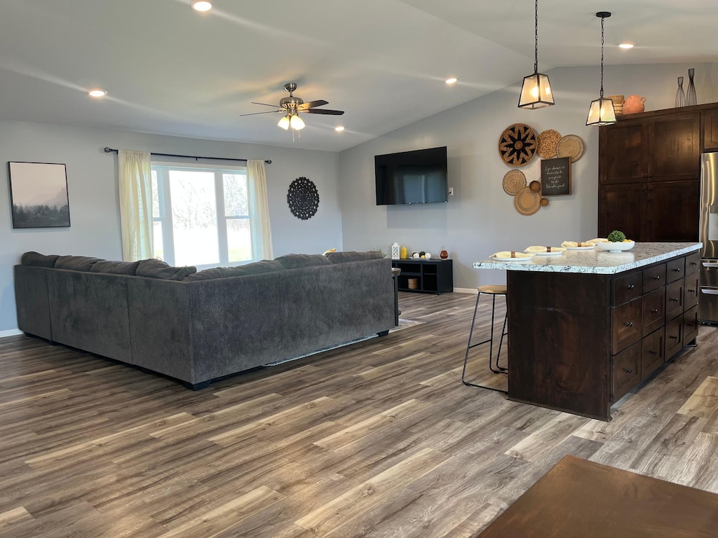 living area with ceiling fan, recessed lighting, baseboards, wood finished floors, and lofted ceiling