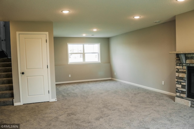 1102 2nd St NW, Delano, MN 55328 - unfurnished living room featuring carpet floors, baseboards, recessed lighting, and a stone fireplace