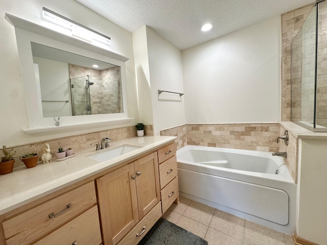 bathroom featuring a stall shower, a bath, vanity, a textured ceiling, and tile patterned floors