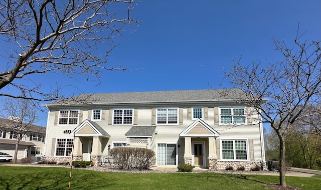 view of front of house with a front yard and stone siding