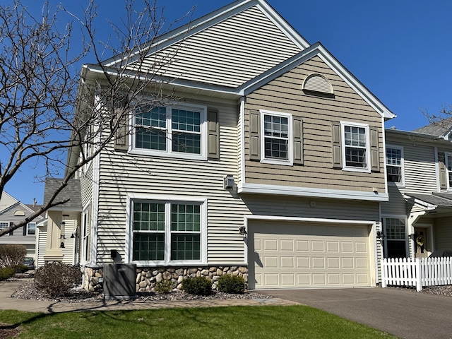 view of front of home with fence, an attached garage, and driveway