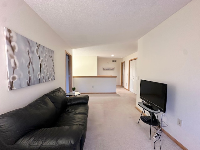 living room with light colored carpet, baseboards, and a textured ceiling