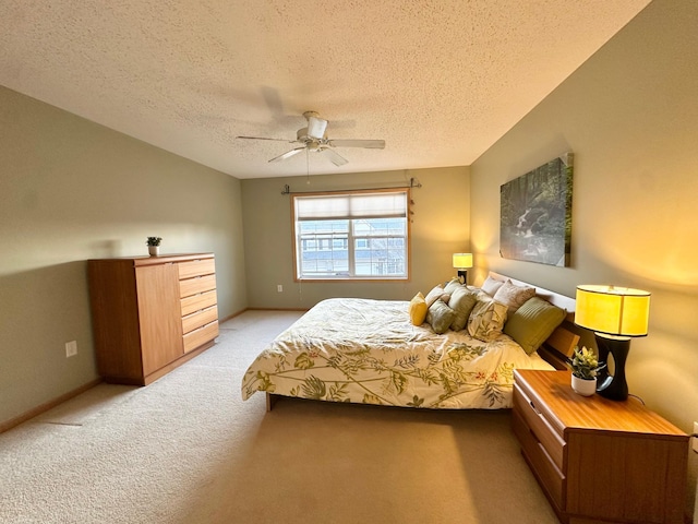 bedroom featuring light colored carpet, a textured ceiling, ceiling fan, and baseboards
