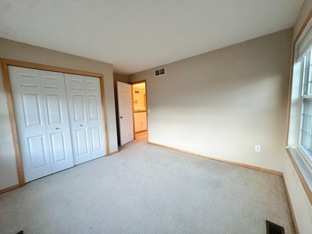 unfurnished bedroom with baseboards, carpet, multiple windows, and a closet