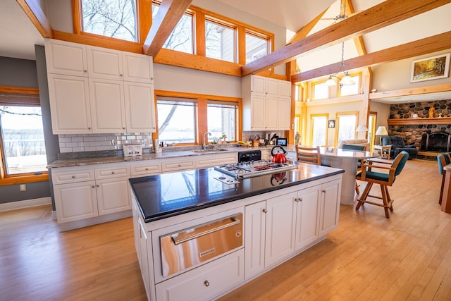 2300 County Road 92, Minnetrista, MN 55359 - kitchen featuring a warming drawer, stovetop, high vaulted ceiling, decorative backsplash, and white cabinetry