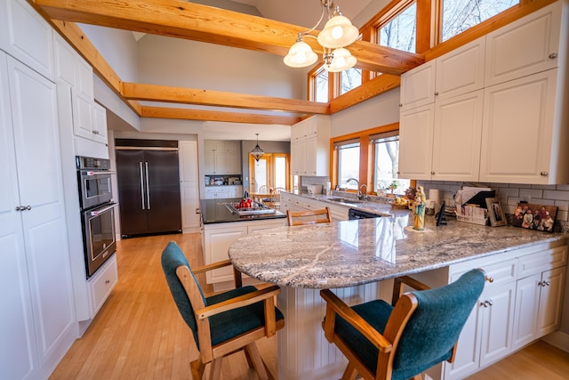 2300 County Road 92, Minnetrista, MN 55359 - kitchen with appliances with stainless steel finishes, a peninsula, decorative backsplash, light wood-style flooring, and healthy amount of natural light
