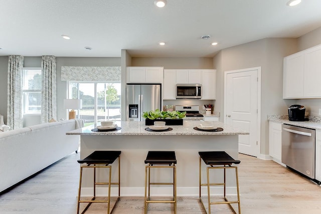 1001 Stone Creek Dr, Jordan, MN 55352 - kitchen with stainless steel appliances, a breakfast bar area, white cabinetry, and recessed lighting