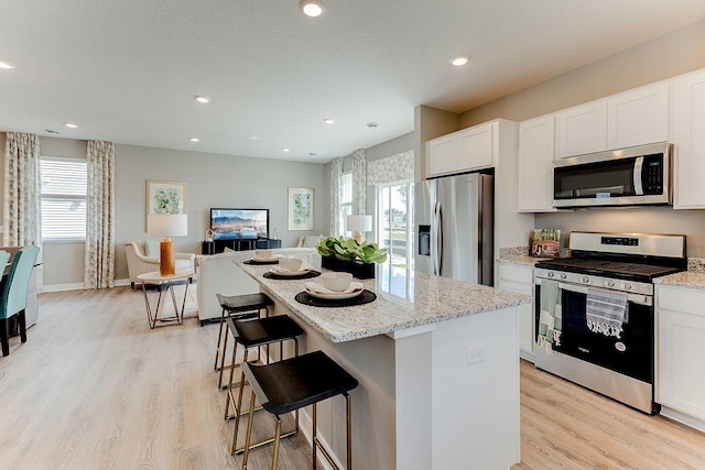 1001 Stone Creek Dr, Jordan, MN 55352 - kitchen featuring appliances with stainless steel finishes, a center island, light stone countertops, white cabinets, and recessed lighting