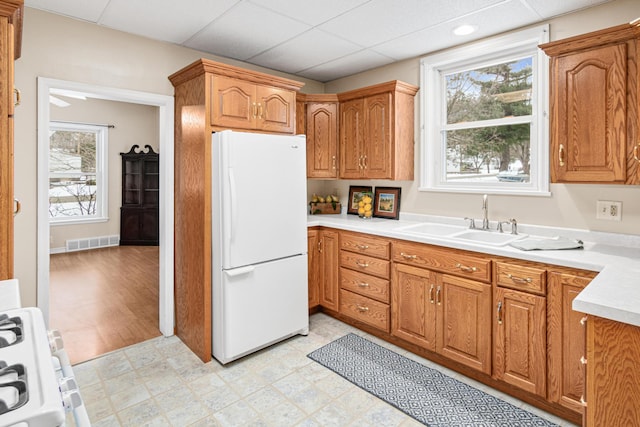 kitchen with a sink, visible vents, light countertops, freestanding refrigerator, and light floors