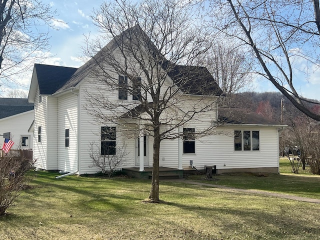 back of house with a lawn and a shingled roof